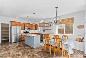 Nicely maintained and updated kitchen area with shiplap walls, granite counters, under cabinet lighting stainless steel appliances, a bench with storage space, and a large pantry.