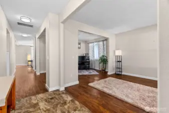 Looking from the entry into the home. A living space or office on the right, dining room or sitting area beyond that. Down the wall to the living room and kitchen.