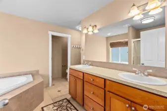 Primary bathroom with tile floors, dual vanity, soaking tub and a large walk in closet.