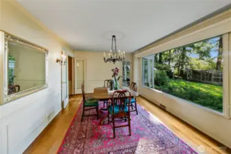 Bathed in sunlight from oversized corner windows, the dining room offers a front-row seat to the changing seasons just outside. With views of both garden and water, the space is perfectly positioned to blur the boundary between indoors and out. Classic detailing, hardwood floors, and the original wall mirror enhance the elegance of this inviting setting—equally suited for quiet morning coffee or celebratory dinners with friends.