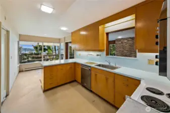 This light-filled kitchen is a preserved time capsule of midcentury design, with vintage cabinetry, cheerful aqua countertops, and generous workspace overlooking the lake. Picture windows flood the room with natural light and frame views of the gardens and water beyond, inviting moments of inspiration while cooking. Whether you choose to restore its retro charm or reimagine it entirely, the space offers an incredible canvas and connection to the surrounding beauty of Evergreen Point.