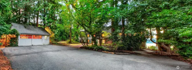 Nestled beneath a canopy of mature trees, the circular drive leads to a spacious motor court framed by a detached garage and the historic main residence. This serene, tree-lined arrival point offers ample guest parking and a quiet welcome to the heart of Evergreen Lakeshore Preserve—where timeless elegance meets the privacy of a forested retreat.