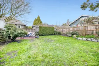 Big backyard with lots of grass and a patio.