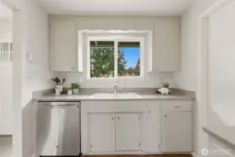 The sink has a window to the front yard and a brand new dishwasher.