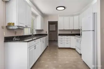 Kitchen features white cabinets with pull out drawers and granite tile counters