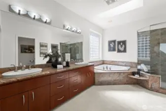 The primary bath with marble countertops, marble surrounded soaking tub, and generous shower.