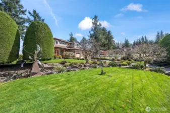 The view from the street looking toward the house - perfectly manicured lawn and landscape beds, complemented by the creative metal art (this piece may be negotiable!)