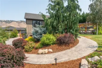 Graceful curved walkway leads through lush, manicured landscaping, creating a stunning approach to the home.