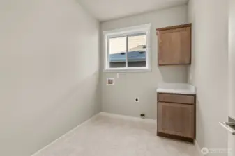Spacious laundry room with cabinets and quartz countertop conveniently located on main floor.