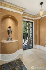Beautiful alcove at the north entry of home, featuring a beautiful display shelf, Fortuny ceiling lamp, and a stunning wrought-iron door with a Tuscan scrollwork design.