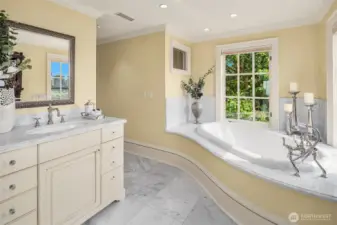Bright and refreshing primary bathroom featuring Carrara marble countertops, slab walk-in shower and bathtub surround, and radiant-heated tile floors.