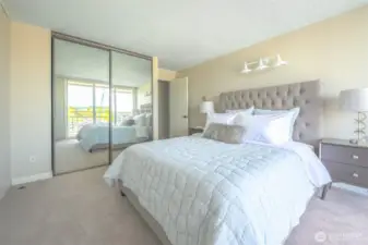 Sunlight filters through mirrored doors in this spacious primary suite—offering generous storage, tranquil tones, and effortless comfort to start and end your day.