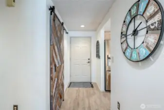 Entryway features a stylish sliding barn door over a closet adorned with shelves. Use it for storage or as a pantry!
