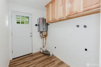 Laundry room with upper cabinets and tankless water heater