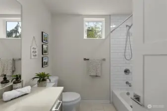 The bathroom's windows bring in natural light, complementing the clean and modern design. A blend of white tile and neutral tones makes this space feel fresh and calming.