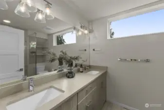 This spacious bathroom features dual sinks, contemporary fixtures, and large windows that fill the room with natural light. It is the perfect retreat to start and end your day.