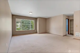 Spacious and bright living room with a large picture window overlooking lush evergreens—your perfect spot to unwind.