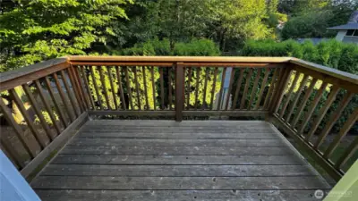 Quiet back porch space with access from the kitchen and tree-lined views.