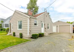 Long driveway featuring plenty of parking spaces with additional covered parking in detached garage
