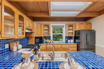 Inviting kitchen with beautiful blue tile countertops that add a pop of color, perfectly balancing the warm, earthy wood tones throughout the home.