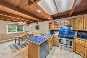 Kitchen overlooking the dining area, featuring a natural gas range and convenient dishwasher for easy daily living.