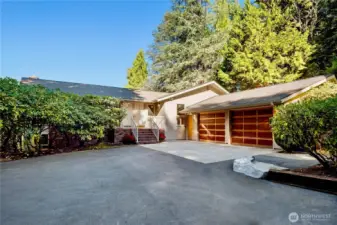 The home’s welcoming entry features double doors and a spacious 2-car garage framed by mature landscaping.