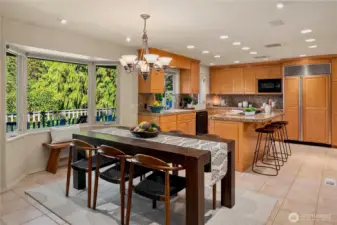 The kitchen combines generous counter space, granite surfaces, and custom cabinetry with natural light and a serene forest outlook.