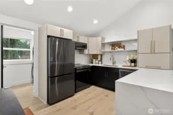 Designer kitchen features quartz countertops with coordinating backsplash, smart appliances, and floating shelves that blend contemporary style with practical storage in this fully remodeled Shoreline home.