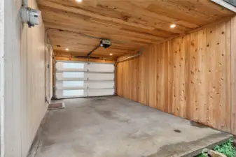 Covered carport with new garage door offers flexible use as protected parking or outdoor living area.