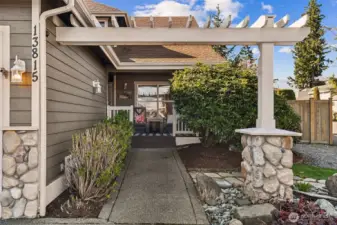 Inviting front entry with a charming pergola-covered walkway leading to a warm and welcoming porch.