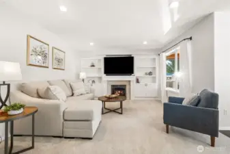Spacious family room featuring a gas fireplace with custom built-in cabinetry, recessed lighting, and large windows that fill the space with natural light. (Plus attached TV stays!)