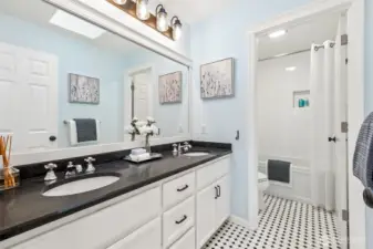 Fresh and inviting upper level bath featuring a spacious double vanity, updated fixtures and lighting, and a classic tub/shower with tile surround and built-in niche.