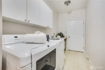 You’ll find a fully outfitted laundry room on your way to the garage. The washer and dryer stay with the home, and just beyond is a utility sink and convenient countertop for folding laundry. The garage door is just ahead!
