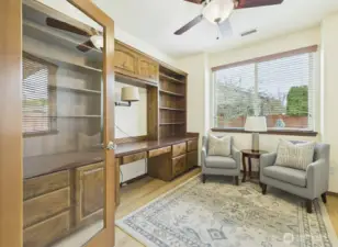 French doors lead to den with custom built-in desk and storage.