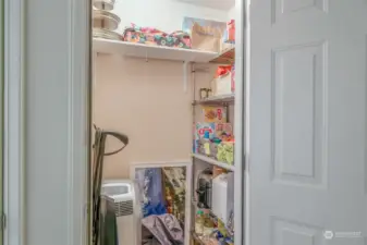 A well-organized storage closet near the units front door with built-in shelving, providing plenty of space for household essentials and everyday items.