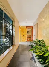 A light-washed passage anchors the home’s internal rhythm, where Venetian-plastered walls and the irrigated planter create a soft threshold between interior calm and the pathways that lead outdoors. From here the circulation extends naturally toward the home’s secondary structures including the bungalow, inviting an easy flow between living spaces and the garden beyond.