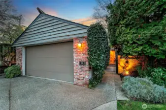 A private, garden-lined approach leads to the Fairway Residence, with mature evergreens and brick detailing creating a sheltered sense of arrival. The attached garage offers direct access while keeping the home set back from the lane, enhancing privacy and reinforcing the quiet, understated character of this mid-century enclave.