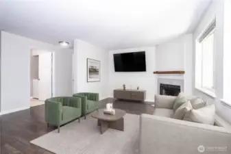 Spacious living room with TV wall, large windows and open sightlines to the kitchen.