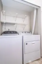Laundry area with built-in shelving and side-by-side washer and dryer.