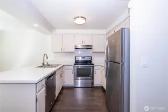 Kitchen with white cabinetry, stainless appliances and peninsula seating.