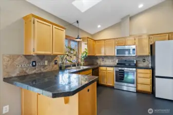 Kitchen boasts granite tile counters, eating bar, SS appliances, & skylights.