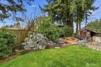 Water feature with waterfall stream with walking bridge and fish pond.