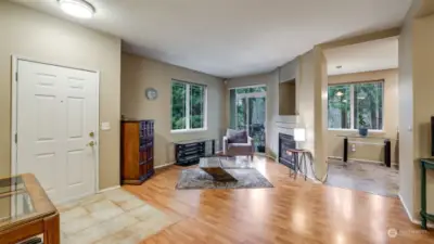 To the left is the front door with a tile entry.  The family room has natural light pouring in with private views.  A view into the into the kitchen.