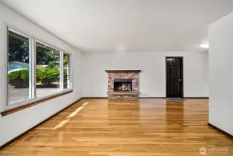 Freshly refinished hardwood floors shine in this bright living room, complemented by a classic brick fireplace for cozy nights in. The upgraded quadruple-pane window package provides excellent natural light while offering noise reduction and energy efficiency.