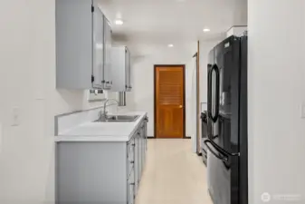 Practical layout with direct access to the laundry room, keeping household chores convenient and tucked away. Modern recessed lighting brightens the space, while painted cabinets offer a timeless, clean look.