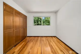 This third bedroom features refinished hardwood floors, a generous wall-to-wall closet for storage, and a large window overlooking the backyard greenery. Bright, neutral walls make it move-in ready and versatile—perfect as a kids’ room, guest bedroom, or home office.