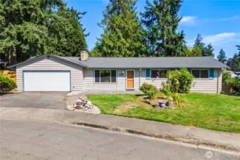 Closer look at the home’s well-maintained exterior with large front windows for natural light, landscaped garden beds, and newer roofline. Positioned slightly above street level, the property showcases great visibility and timeless curb appeal.