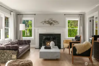 The living room is filled with natural light (western and southern facing) windows. Shaw wide-plank oak floors and intricate millwork ground the space in timeless craftsmanship.