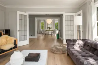 From the living room, glass-paneled doors frame a view through the gracious foyer into the dining room, highlighting the home’s effortless flow. Authentic Noguchi lighting and serene window coverings really tie the space together.