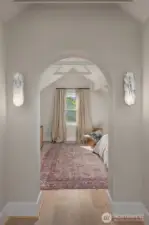 Arched passageways and marble sconces introduce the serene primary suite, where vaulted ceilings and natural light create a calming sanctuary.